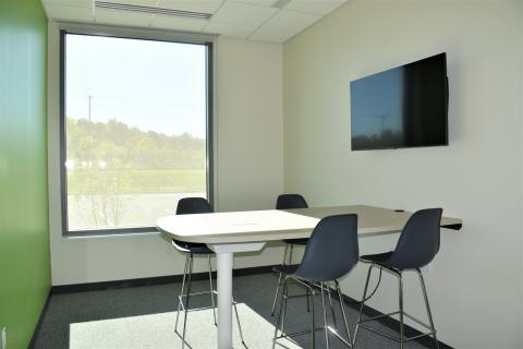 A high-top table attached to the wall with four chairs and a mounted television.