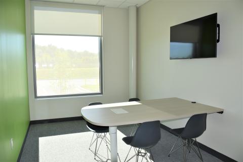 A table attached to the wall with four chairs and a mounted television.