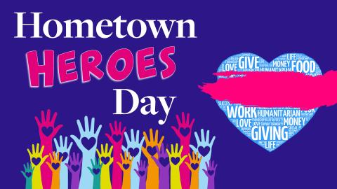 Image reads "Hometown Heroes Day" against a navy background. Colorful hands being raised are under the title and a heart is to the right of the title.