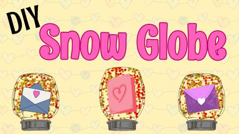 Image reads "DIY Snow Globe" against a pale yellow background. Three snow globes are under the title with gold and red glitter and cardstock Valentine's Day cards are inside the snow globes.