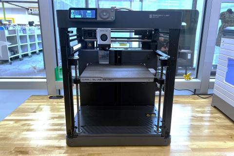 Image shows a Bambu Labs 3D printer sitting on a table.