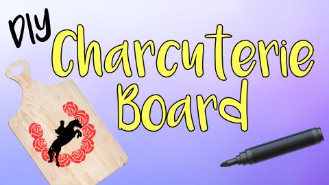 Image reads "DIY Charcuterie Board" against a gradient background. A decorated charcuterie board is to the left of the title. A paint marker is to the right of the title.