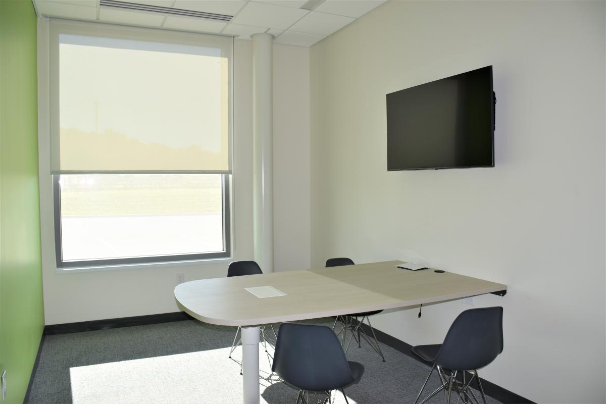 A table attached to the wall with four chairs and a mounted television.