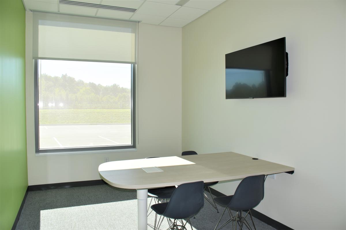 A table attached to the wall with four chairs and a mounted television.