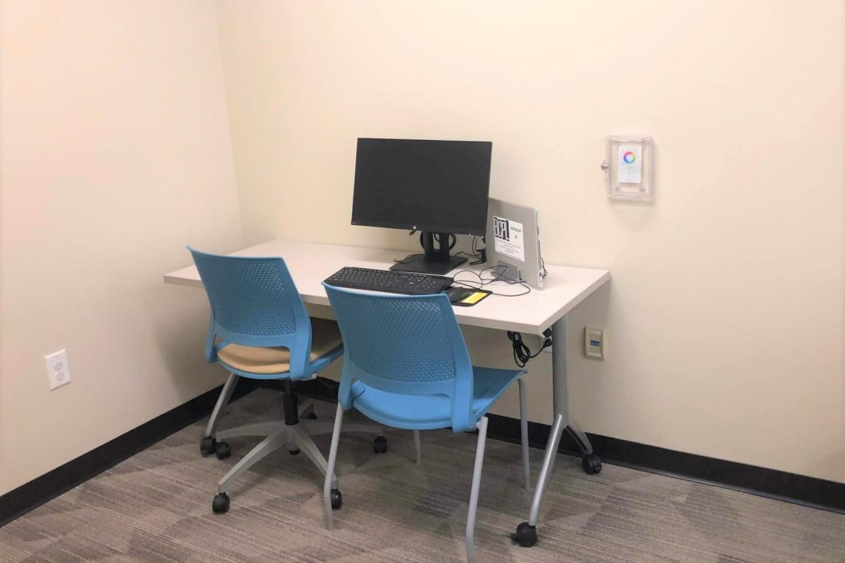 A desk with a computer, two chairs, and a laptop.