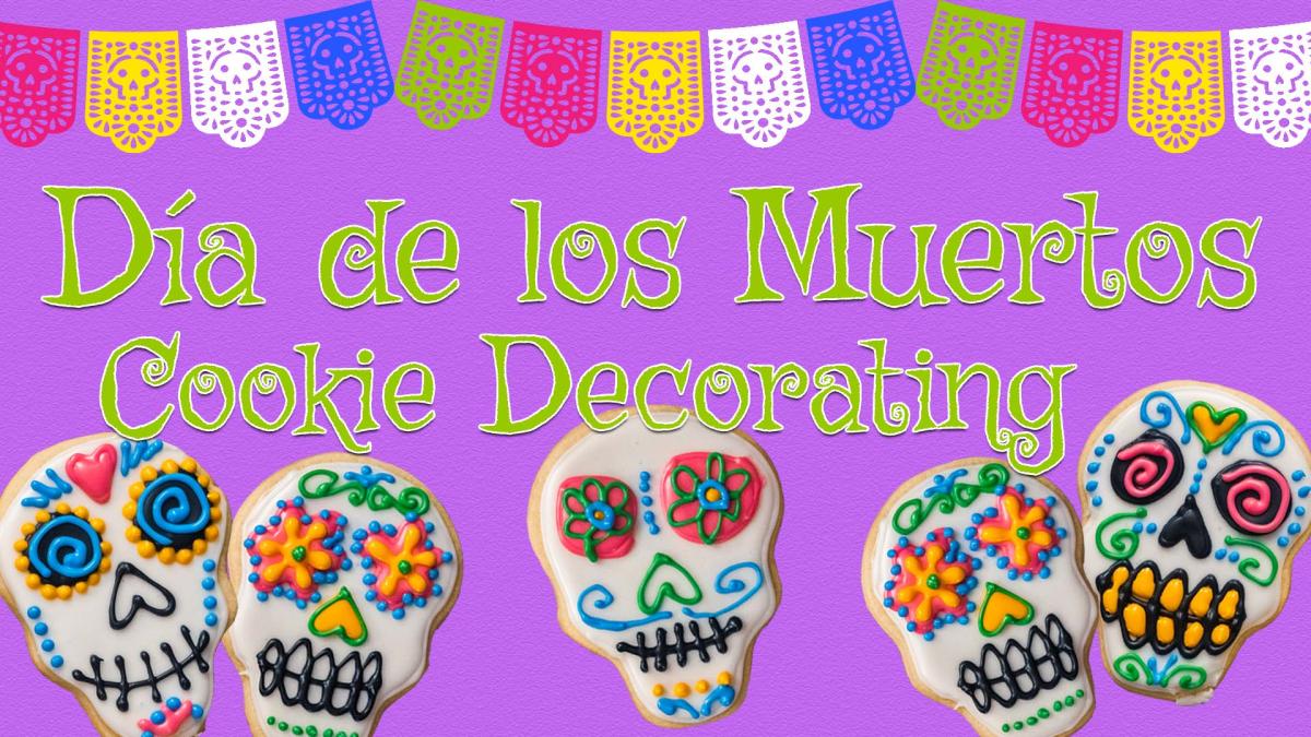 Image reads "Dia de los Muertos Cookie Decorating" against a purple textured background. To the left and right of the text are decorated sugar skull cookies. A colorful banner takes up the top portion of the image. 