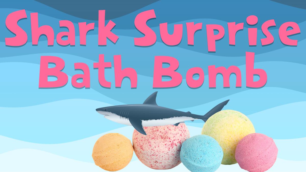 Image reads "Shark Surprise Bath Bomb" against a blue wavy background. Bath bombs and a shark figure are under the title.