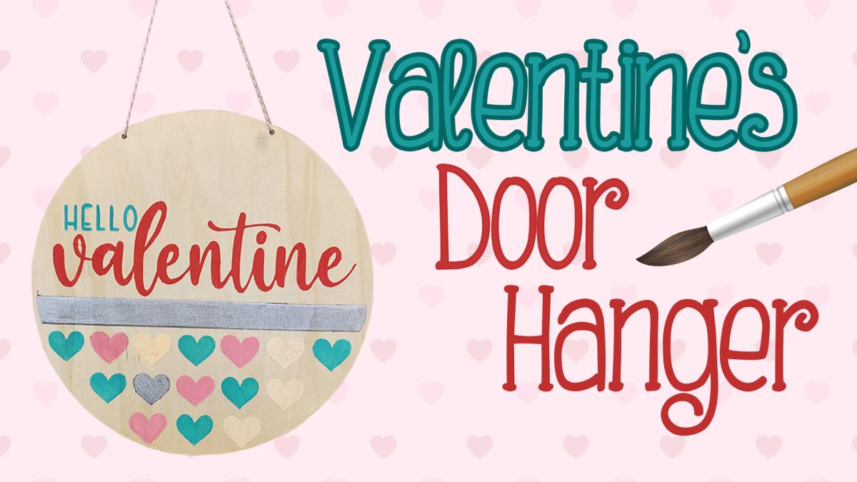 Image reads "Valentine's Door Hanger" against a pink background. A paintbrush is to the right of the title. A painted wooden door hanger is to the left of the title.
